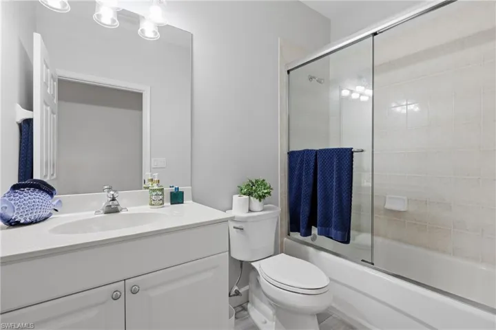 Bathroom featuring a white vanity with an integrated sink, polished chrome faucet, and a large wall mirror