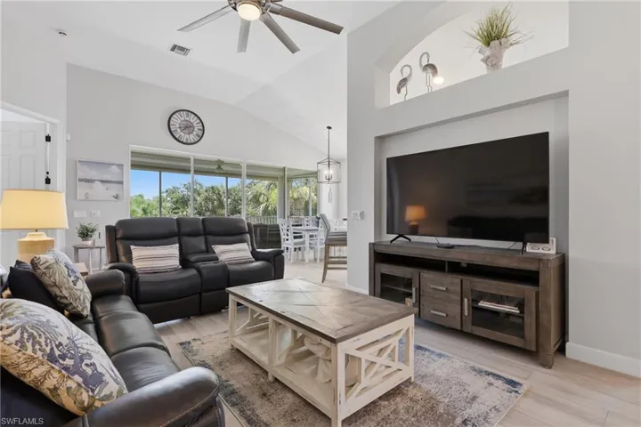 Vaulted ceilings with a ceiling fan, wood-finish flooring, and a built-in media niche with an arched display shelf