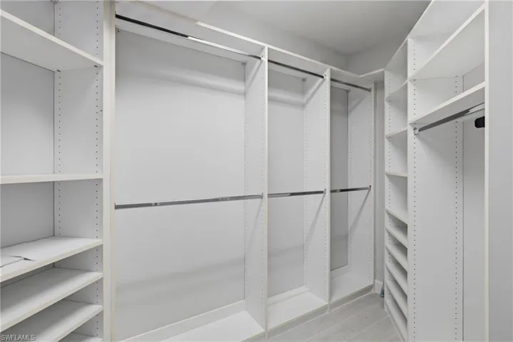 Custom closet system featuring white shelving, multiple hanging rods, corner shelving, and integrated shoe racks