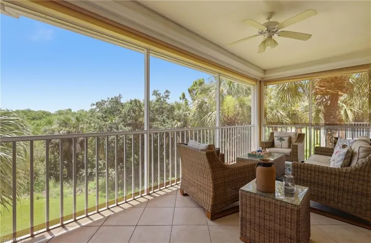 Screened balcony featuring a ceiling fan, light-toned tile flooring, and a metal railing