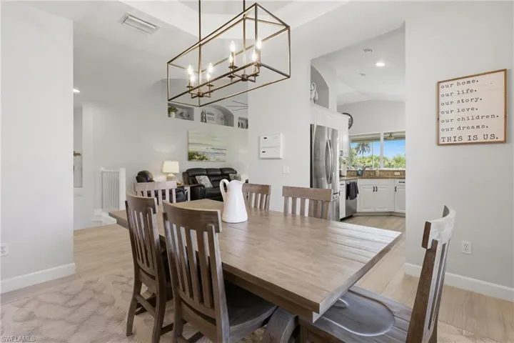 Dining area featuring a rectangular bronze-finish chandelier, vaulted ceilings, and light wood-finish flooring