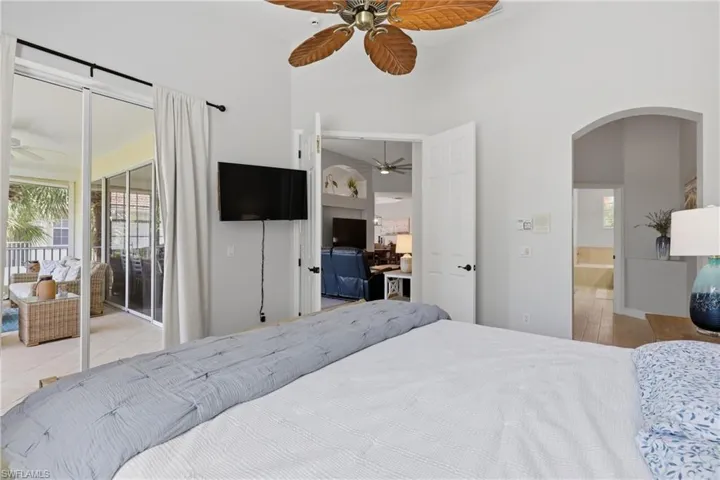Vaulted ceiling room with an overhead fan, featuring large glass sliding doors opening to a screened-in patio