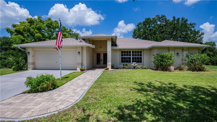 View of front facade featuring a garage and a front lawn