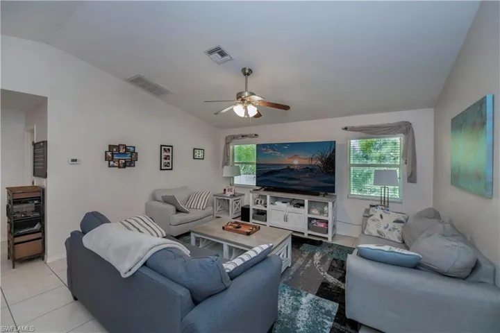 Tiled living room featuring ceiling fan and vaulted ceiling
