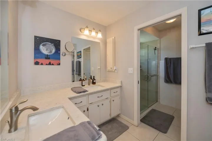Bathroom with a shower with door, tile patterned flooring, and double vanity