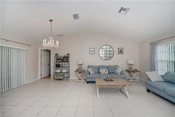 Tiled living room featuring a notable chandelier and vaulted ceiling
