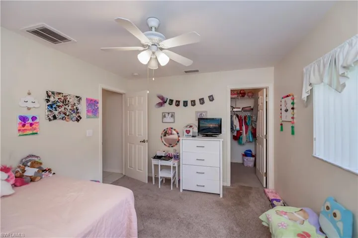 Carpeted bedroom with a walk in closet, a closet, and ceiling fan