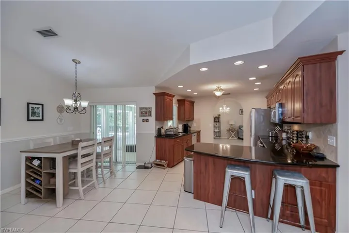 Kitchen with tasteful backsplash, stainless steel appliances, kitchen peninsula, light tile patterned floors, and a chandelier