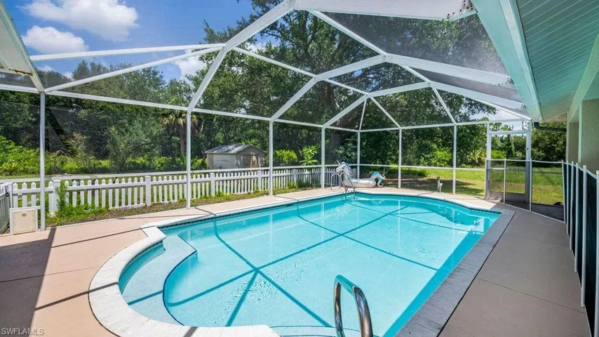 View of pool featuring a storage shed, a patio, and glass enclosure