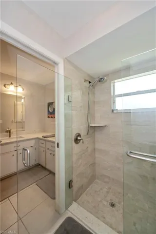 Bathroom with double sink vanity, an enclosed shower, and tile patterned flooring
