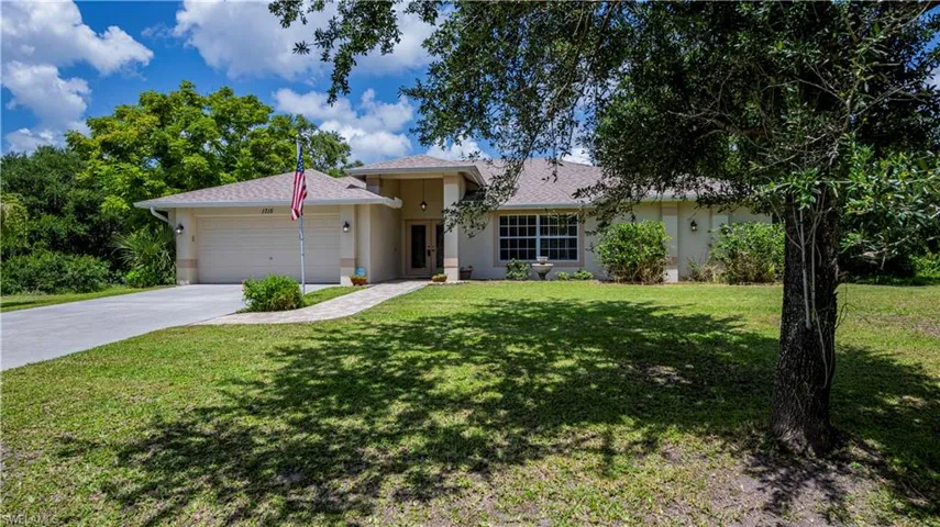 Ranch-style home featuring a garage and a front yard