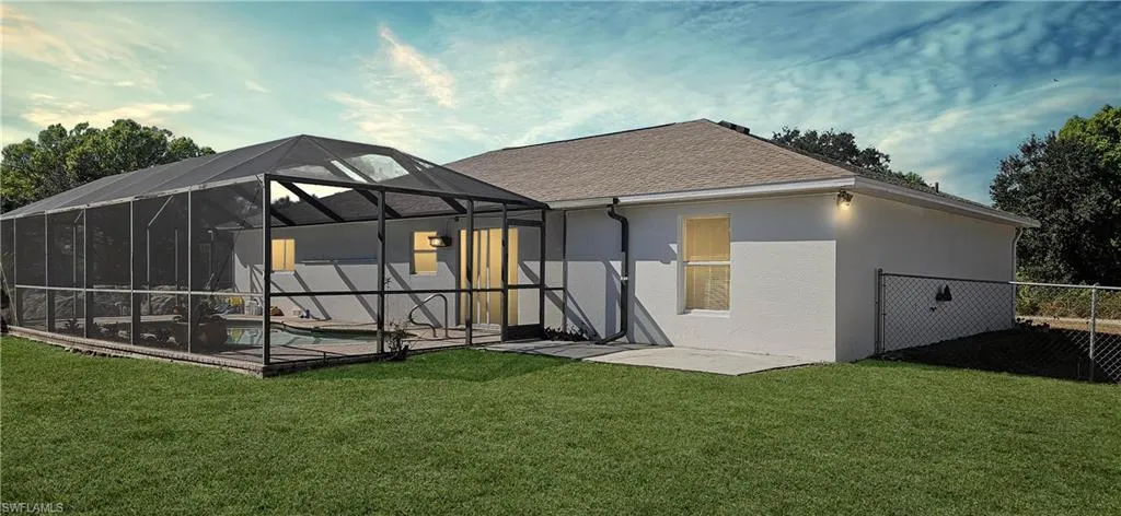 Back of property with stucco siding, a lanai, a pool, a sunroom, and a shingled roof
