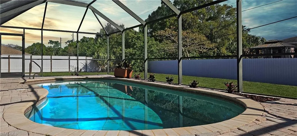 View of pool with a fenced backyard, a lanai, patio surround, and a sunroom