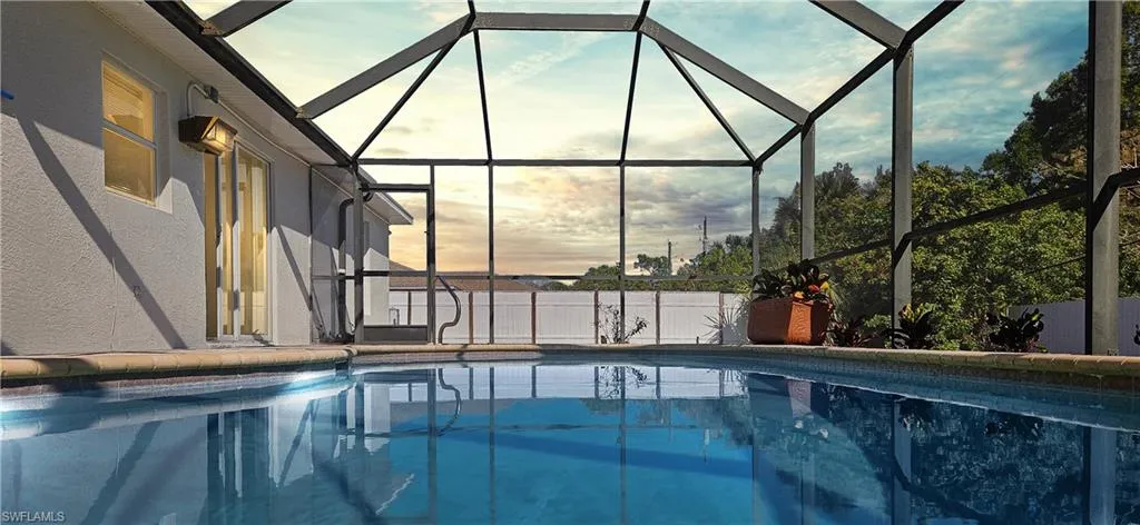 Pool at dusk featuring a sunroom and glass enclosure
