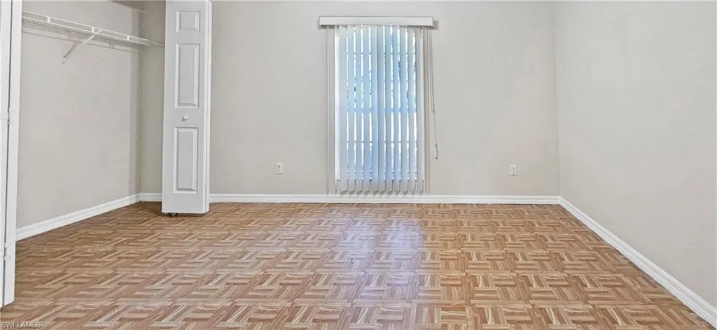 Unfurnished bedroom featuring a closet and parquet floors