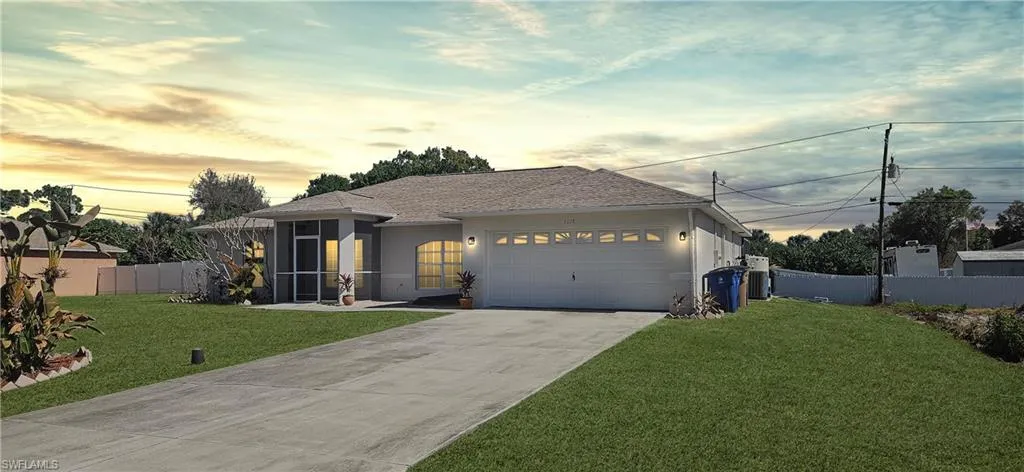 Ranch-style home featuring driveway, stucco siding, a garage, a shingled roof, and a sunroom