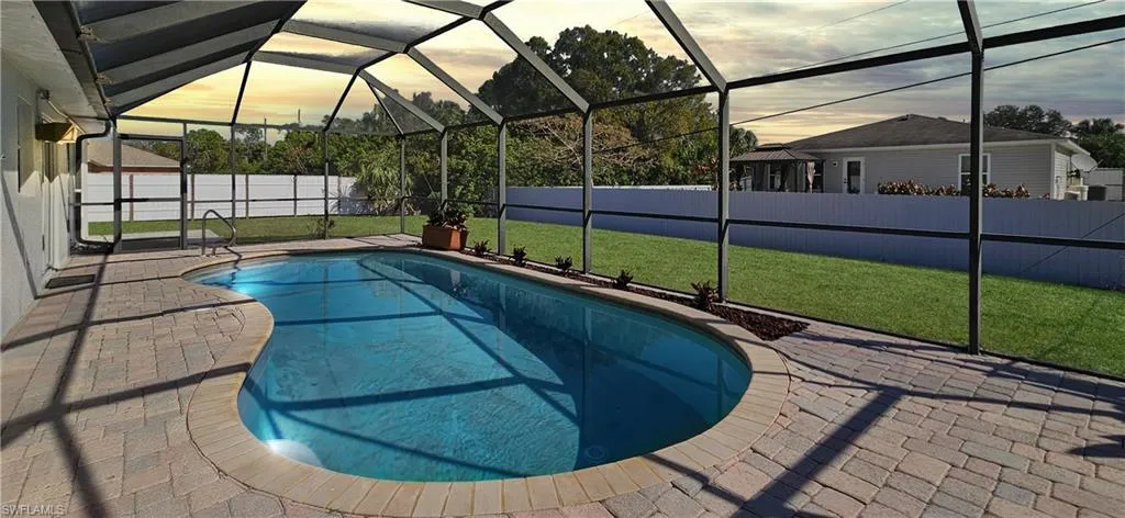 Pool at dusk featuring a fenced backyard, a sunroom, a patio, and a lanai