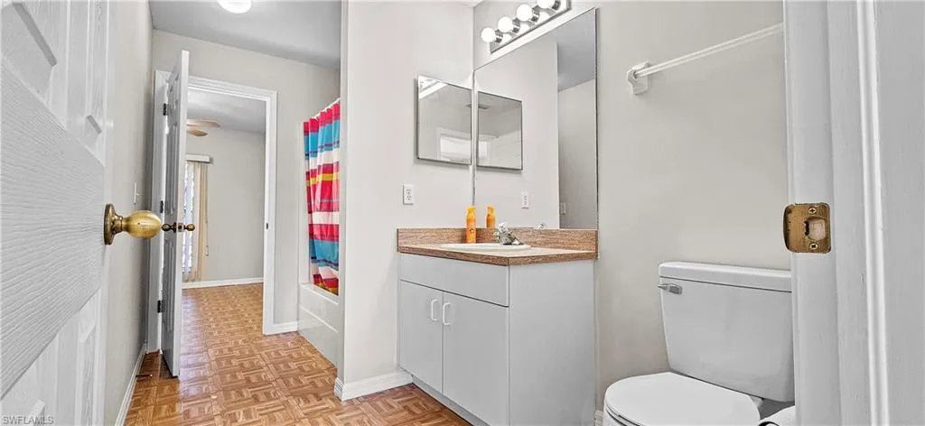 Bathroom with vanity, parquet floors, and shower / tub combo with curtain