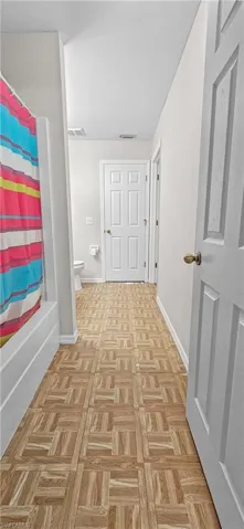 Bathroom with shower / tub combo and parquet floors