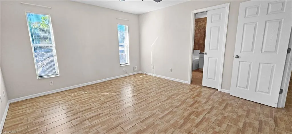 Unfurnished bedroom with light wood finished floors, a ceiling fan, and ensuite bathroom