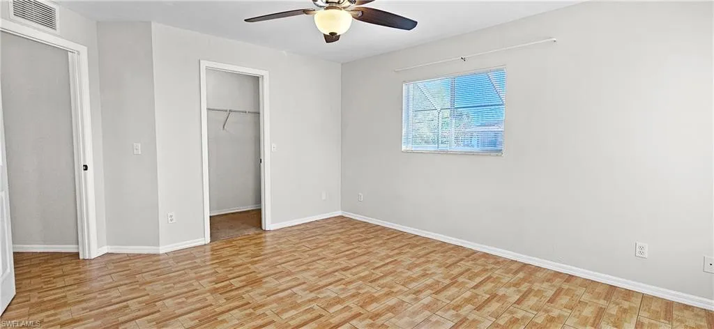 Unfurnished bedroom with light wood-type flooring, a spacious closet, and ceiling fan
