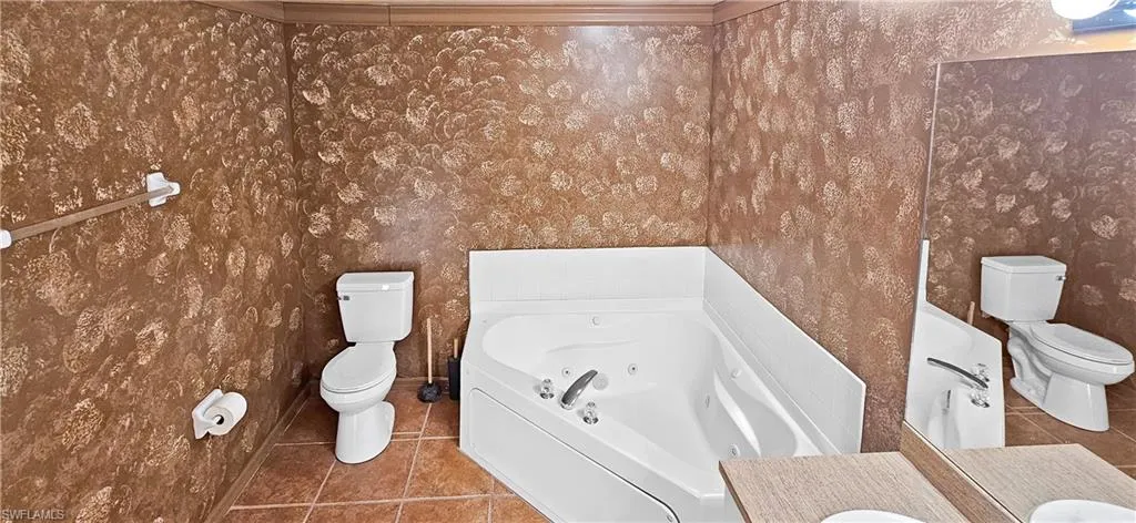 Full bathroom featuring a jetted tub, tile patterned floors, and vanity