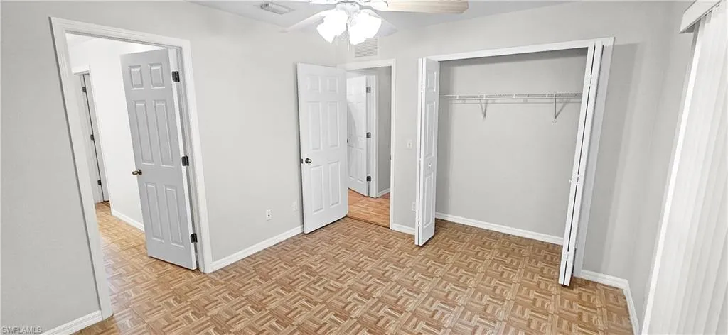 Unfurnished bedroom with parquet floors, a closet, and a ceiling fan