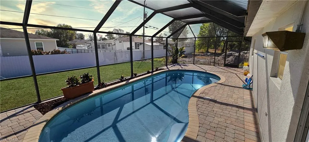 Swimming pool featuring a sunroom, a patio area, glass enclosure, and a fenced backyard