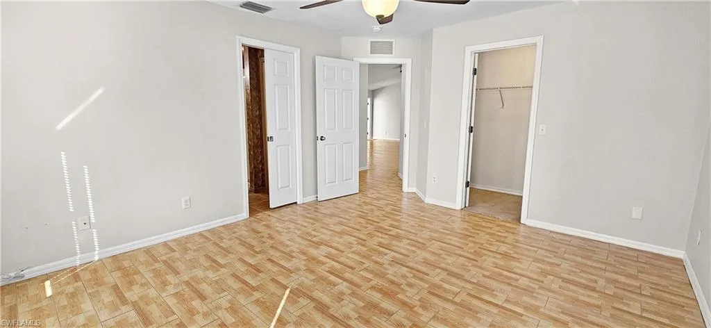 Unfurnished bedroom with a spacious closet, light wood-type flooring, and ceiling fan