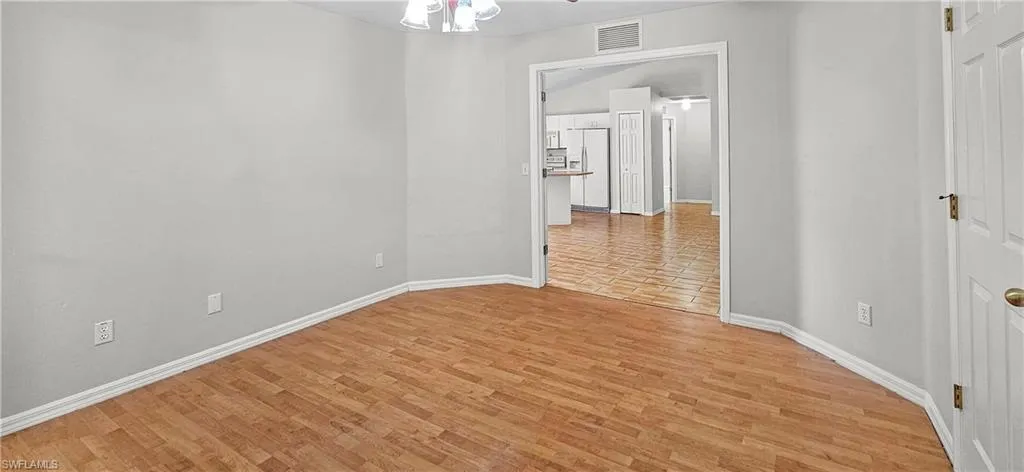 Unfurnished room featuring light wood finished floors and a chandelier