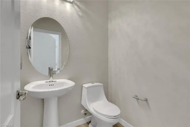 Half bathroom with toilet and a textured wall