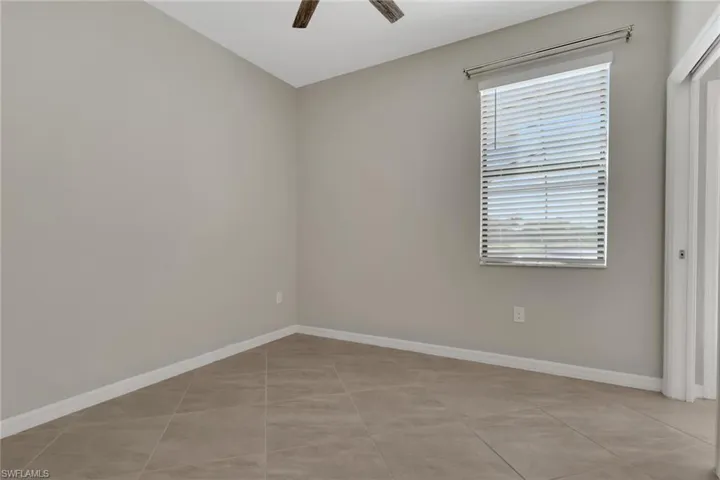 Empty room with a ceiling fan and light tile patterned floors