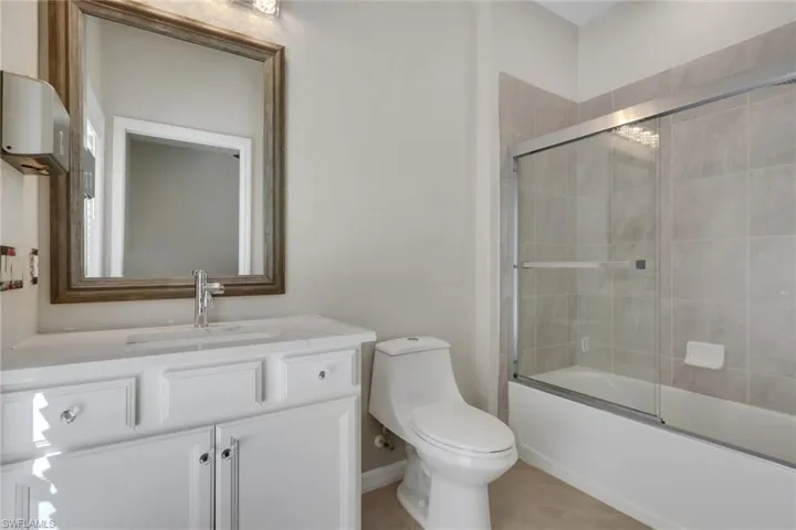 Bathroom featuring vanity and bath / shower combo with glass door