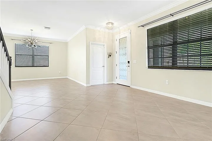 Spare room featuring a chandelier, light tile patterned floors, and crown molding