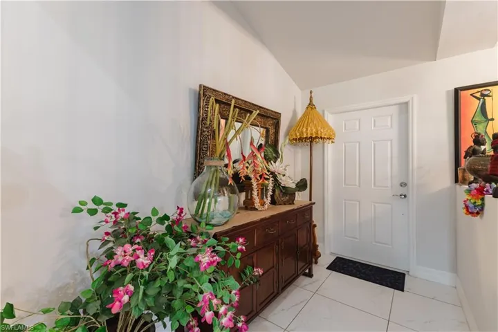Foyer with light marble finish flooring and lofted ceiling
