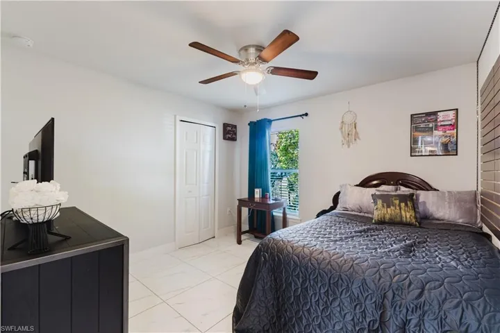 Bedroom with light marble finish flooring, a closet, and a ceiling fan