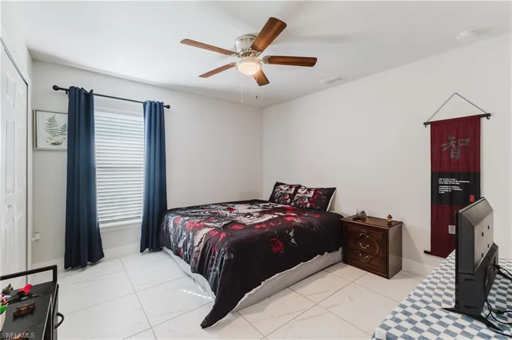 Bedroom with ceiling fan and light marble finish flooring