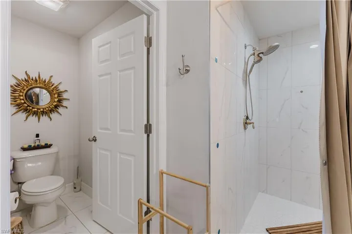 Bathroom with a stall shower and marble look tiles
