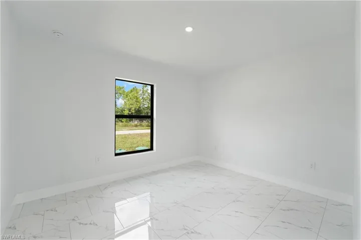 Recessed lighting, tile flooring, white walls, and a single window with black trim