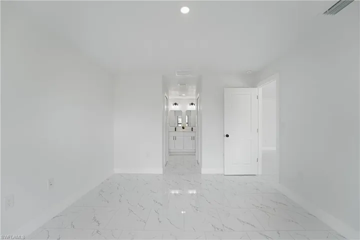White walls, large format tile flooring, recessed lighting, and a white paneled door