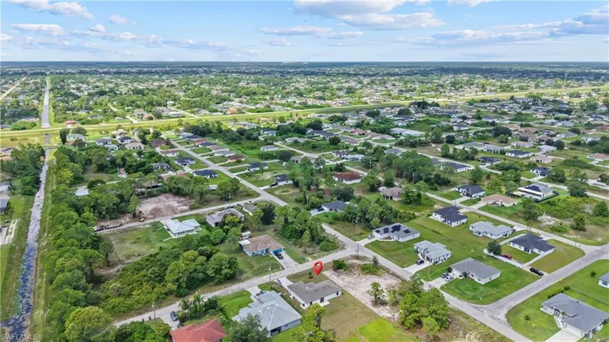 Residential neighborhood featuring a mix of established homes and undeveloped lots, surrounded by mature trees and natural areas