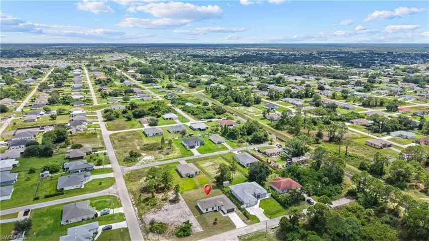 Aerial perspective of a residential area featuring single-story homes, paved roads, and extensive green spaces
