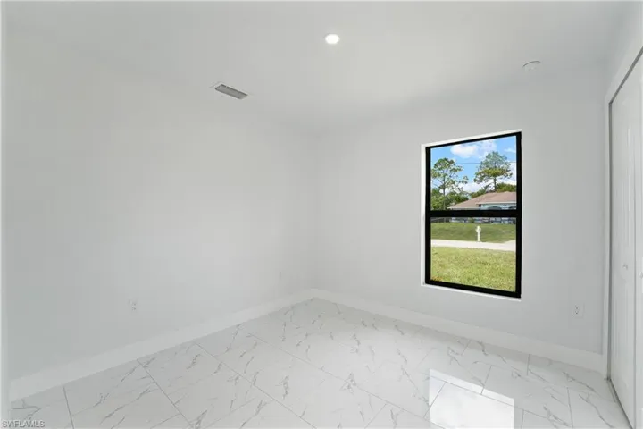 White walls, recessed lighting, and a window with a black frame
