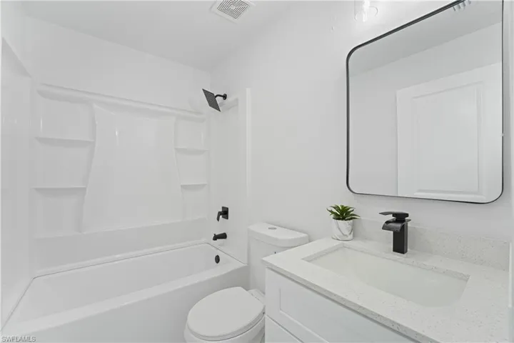 White vanity with a light-toned countertop, integrated sink, and matte black faucet