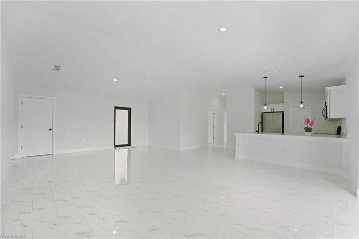 White tile flooring with subtle veining, recessed lighting, white cabinetry, and pendant light fixtures