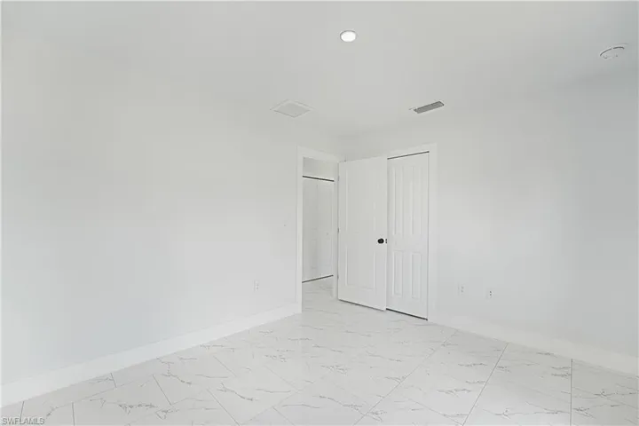 White walls with a matte finish, recessed ceiling lighting, and white baseboards