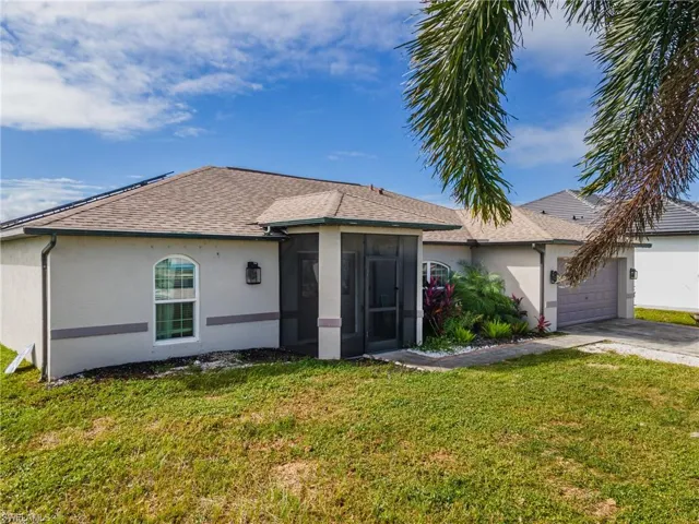 Stucco exterior featuring a screened entry, arched window detailing, multi-faceted roofline, and attached garage