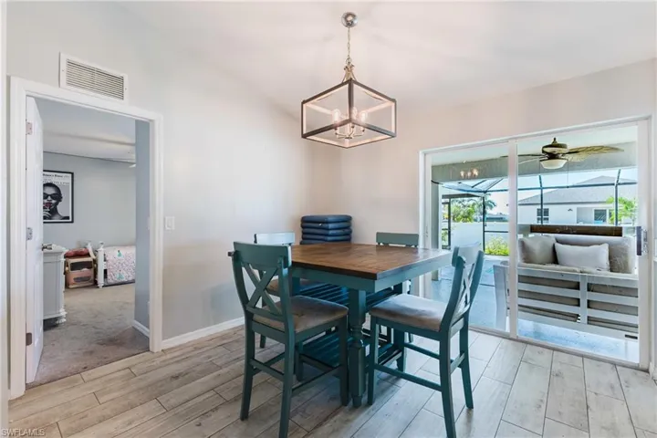 Vaulted ceilings, wood-finish tile flooring, geometric metal pendant lighting, and large sliding glass doors providing outdoor access
