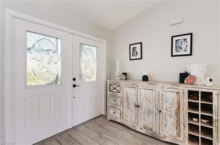Entryway featuring white dual front doors with decorative oval glass inserts, matte black hardware, and wood-finish tile flooring