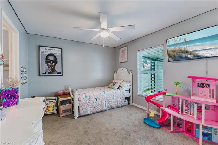 Neutral-toned room featuring neutral carpeting, a ceiling fan with integrated lighting, and a single-pane window with white blinds